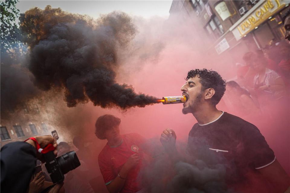  Ein marokkanischer Fan hält im New Yorker Stadtteil Queens eine Leuchtfackel mit dem Mund, nachdem die Mannschaft das Viertelfinalspiel der Fußball-Weltmeisterschaft gegen Frankreich verloren hat.Ryan Murphy/AP/dpa