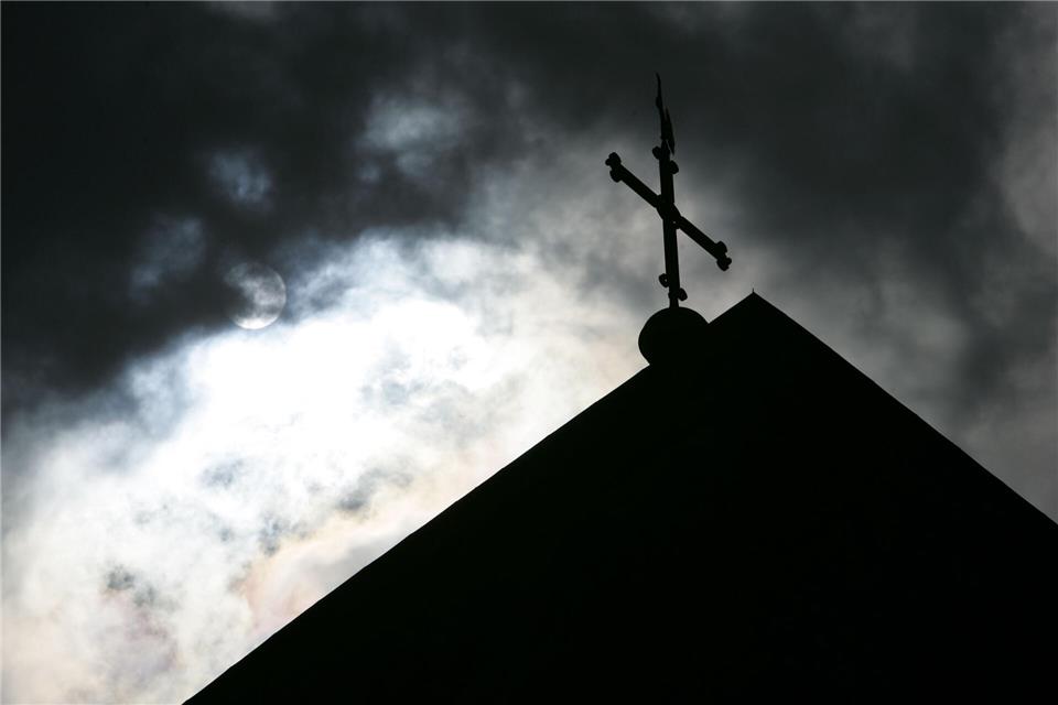 ARCHIV - 18.05.2008, Niedersachsen, Osnabrück: SYMBOLBILD - Im Gegenlicht und vor wolkenverhangenem Himmel ist die Kirchturmspitze des Doms mit Kreuz zu sehen. (zu dpa „Katholische Kirche beschäftigt sich erneut mit dem Thema sexueller Missbrauch“ vom 23.11.2018) Foto: Friso Gentsch/dpa +++ dpa-Bildfunk +++picture alliance/dpa