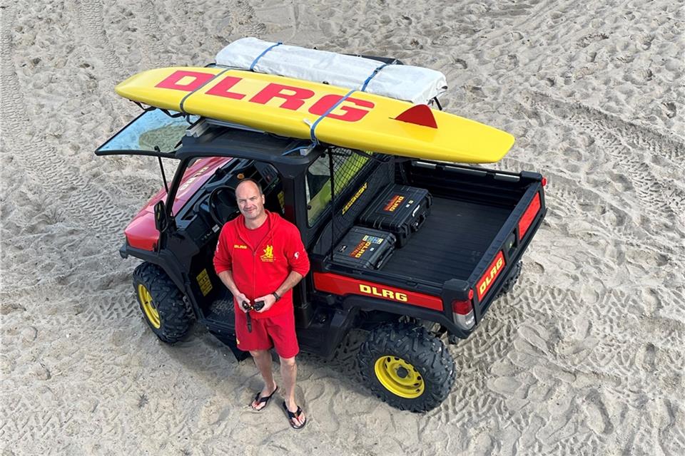 Achim Böhm von der DLRG Heiden hält Rettungswache an der Ostsee am Timmendorfer Strand. Das Brett auf dem Dach des geländegängigen Gefährts ist nicht zum Surfen, sondern ein Rettungsbrett.