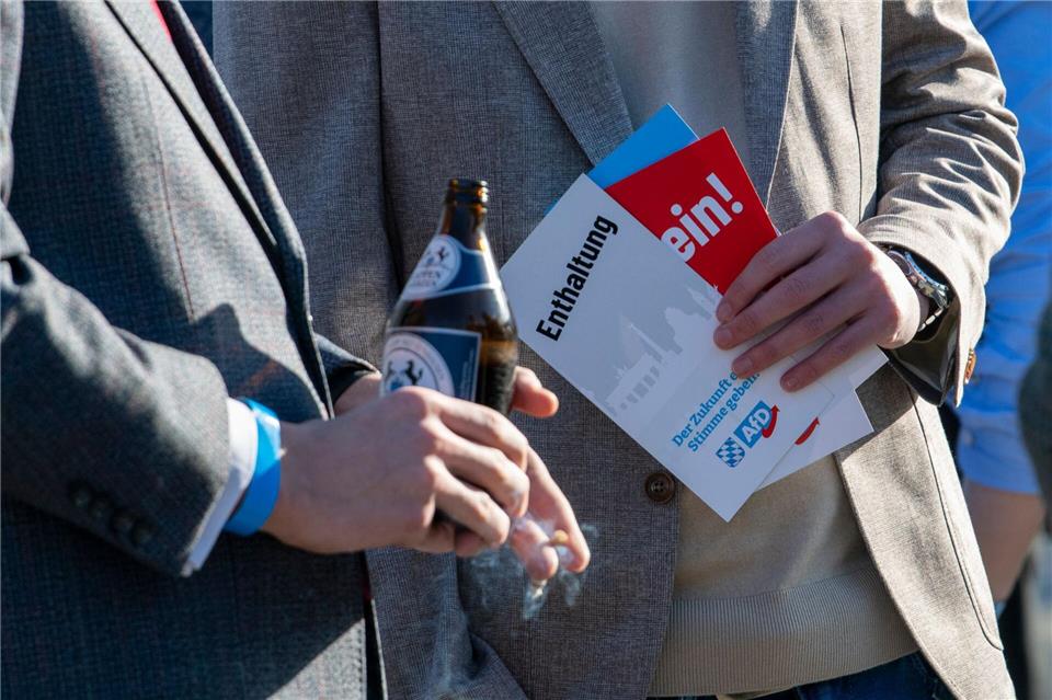 AfD-Anhänger stehen mit Stimmkarten und einer Bierflasche zusammen.Stefan Puchner/dpa