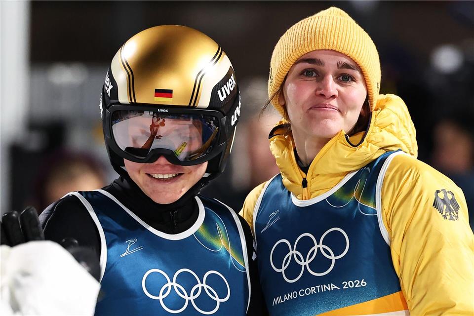Agnes Reisch (l, Deutschland) reagiert nach ihrem Sprung von der Großschanze neben Teamkollegin Selina Freitag (Deutschland) bei den Olympischen Winterspielen Mailand Cortina 2026.Daniel Karmann/dpa