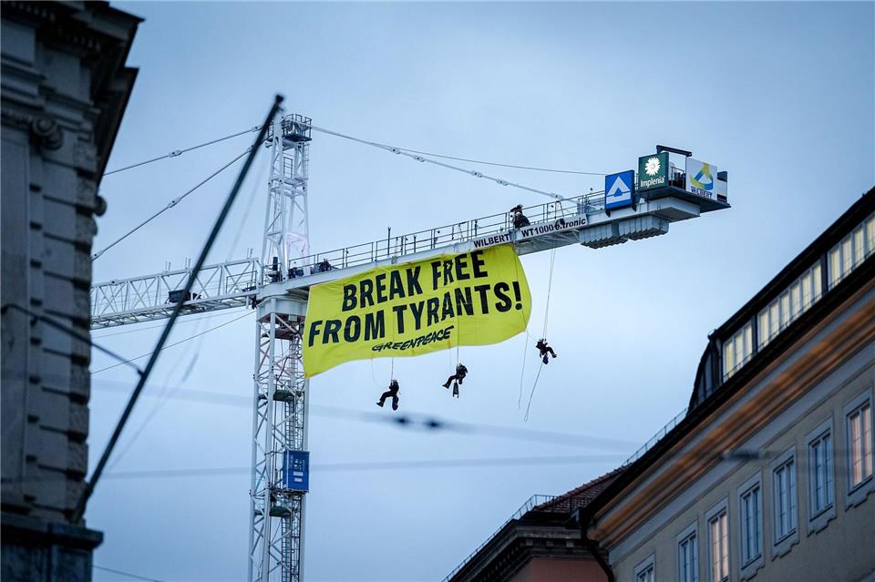 Aktivisten seilen sich von einem Kran in der Nähe der Münchner Sicherheitskonferenz ab.Kay Nietfeld/dpa