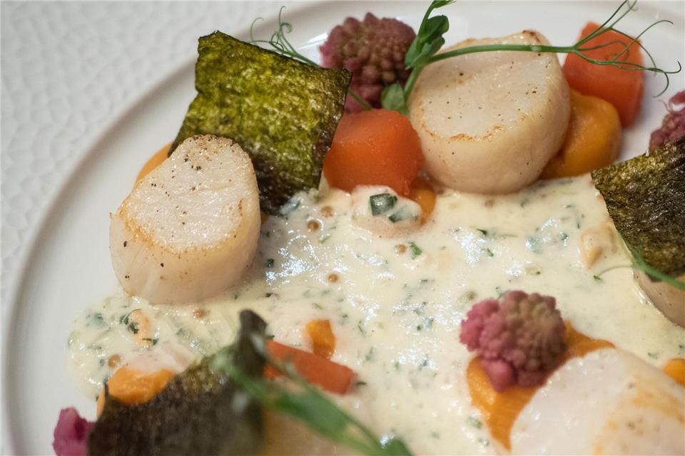 Alexis Tison bereitet die Jakobsmuscheln auf Süßkartoffelpüree und mit einer Creme-Fraiche-Sauce zu.Andreas Drouve/dpa-tmn