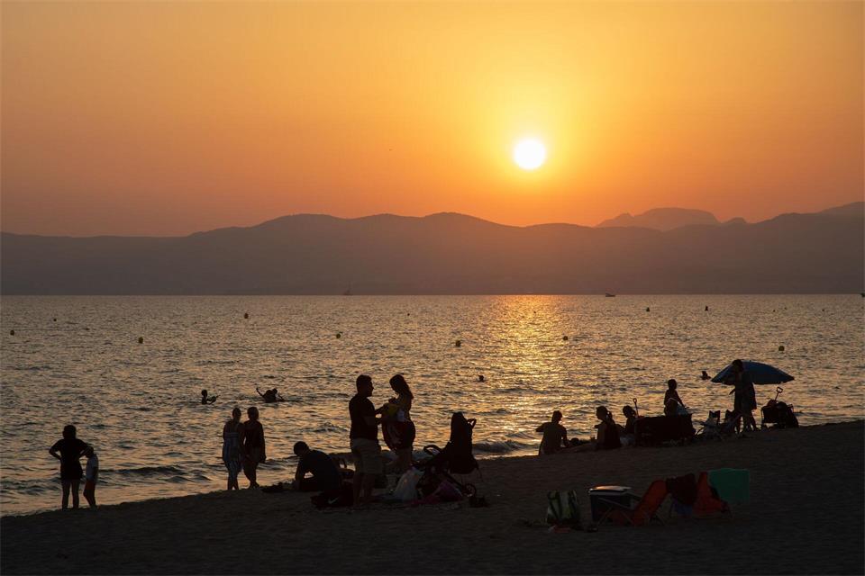 Am Strand von Playa de Palma auf Mallorca baden Menschen bei Sonnenuntergang im Meer. (Archivbild)Clara Margais/dpa