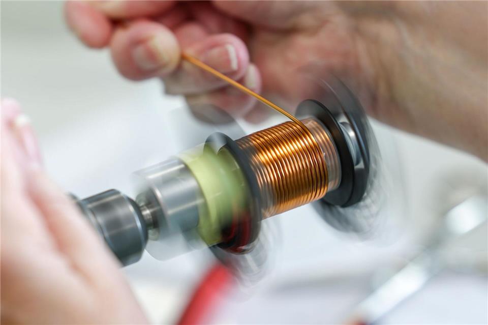 An einer Maschine wickelt eine Mitarbeiterin eine Spule für eine PFC-Drossel. Jan Woitas/dpa