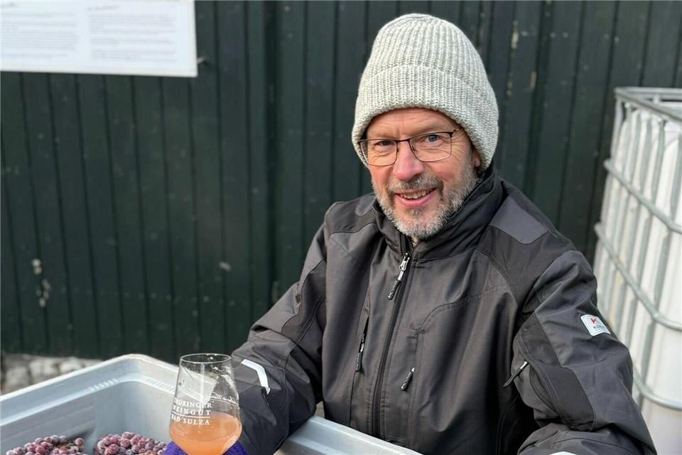 Andreas Clauß freut sich über den geernteten Eiswein. Kathrin Clauß/Thüringer Weingut Bad Sulza/dpa