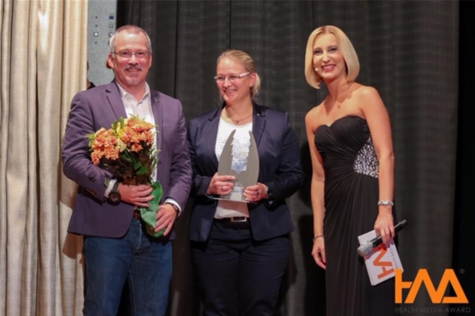 Andreas und Patricia Funke (rechts die Moderatorin der Preisverleihung) freuen sich über die Auszeichnung.