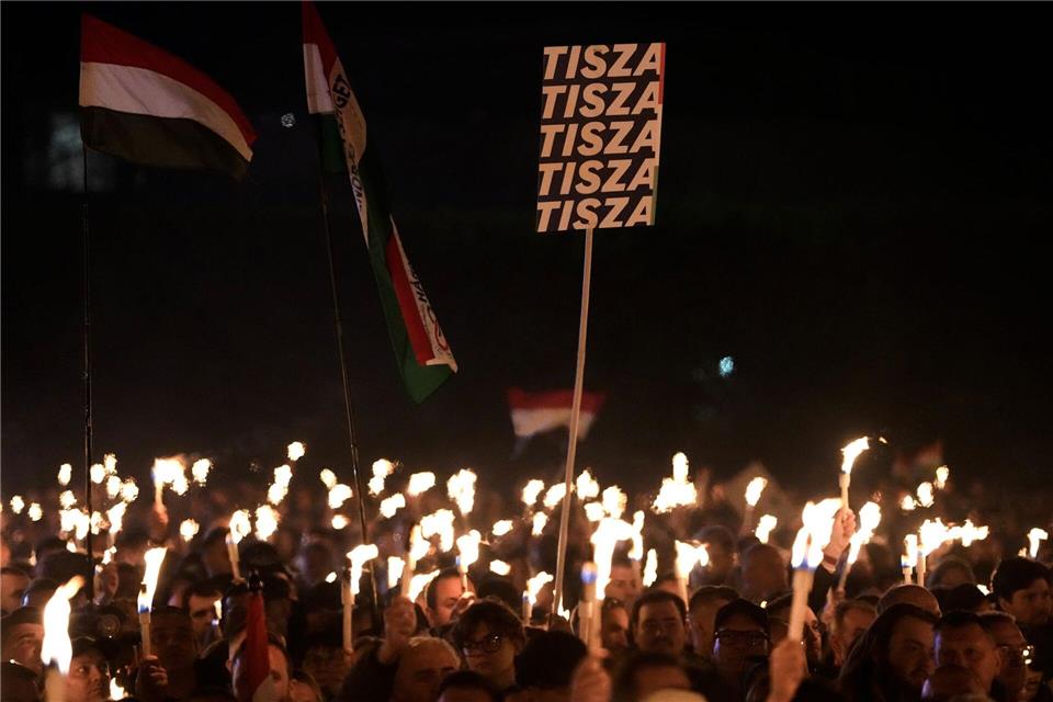 Anhänger von Peter Magyar, dem Vorsitzenden der oppositionellen Tisza-Partei, halten bei der Wahlkampfveranstaltung ihre beleuchteten Handys hoch.Darko Bandic/AP/dpa