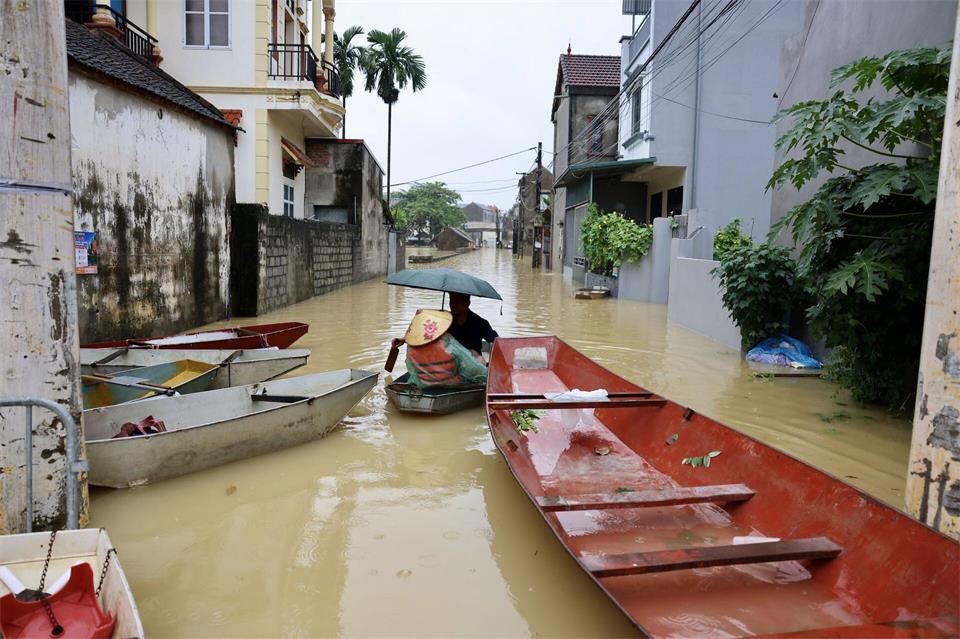 Anwohner fahren mit einem Boot durch ein überflutetes Dorf in Vietnam.Nhat Anh/VNA/AP/dpa