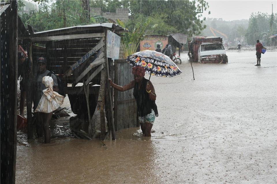 Anwohner waten durch eine überflutete Straße nach dem durchzug von Hurrikan Melissa in Petit-Goave.Odelyn Joseph/AP/dpa