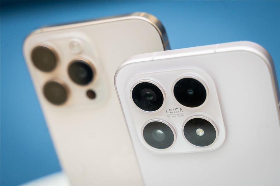 Apple verlangt einen Aufpreis für eine dedizierte Teleobjektivlinse bei seinen Pro-iPhones (im Hintergrund), während Xiaomi in seinem Basismodell Xiaomi 17 (im Vordergrund) ein Zoomobjektiv standardmäßig integriert.Zacharie Scheurer/dpa-tmn