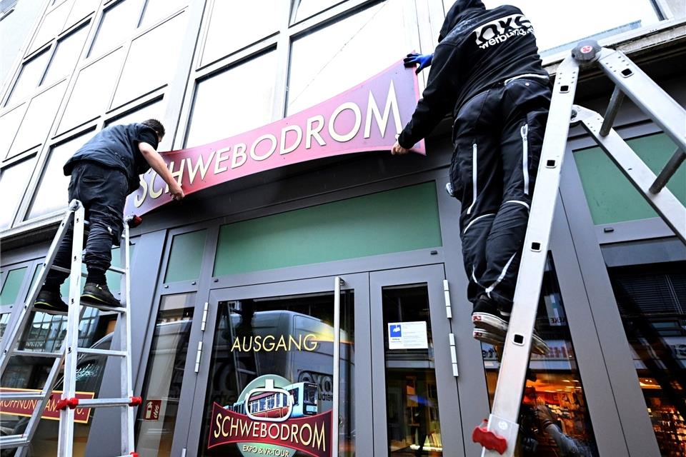 Arbeiter befestigen das Schild an den Räumlichkeiten des neuen Museums "Schwebodrom".