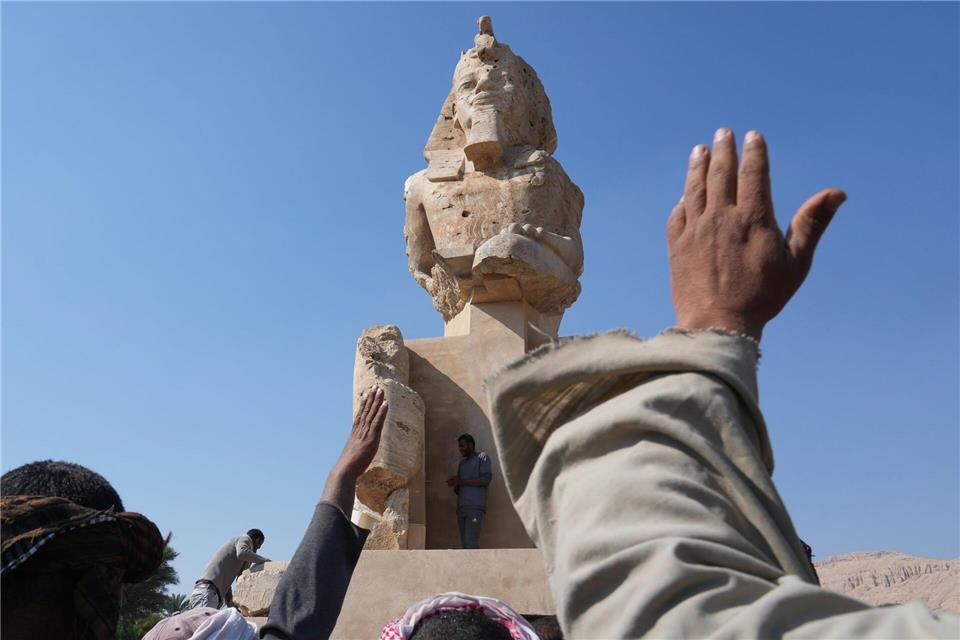 Arbeiter der Antikenverwaltung feiern, nachdem sie eine riesige Alabasterstatue für den Pharao Amenhotep III. in Luxor enthüllt haben.Amr Nabil/AP/dpa