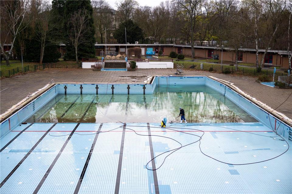 Arne Wagenknecht, Rettungsschwimmer und Mitarbeiter der Berliner Bäder-Betriebe, reinigt die Fliesen im Schwimmbecken vom Sommerbad.Christophe Gateau/dpa