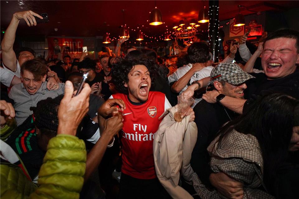 Arsenal-Anhänger feiern in einem Pub in der Nähe des Arsenal-Stadions, nachdem die Fußballmannschaft des FC Arsenal den Titel in der Premier League gewonnen hat.Alberto Pezzali/AP/dpa