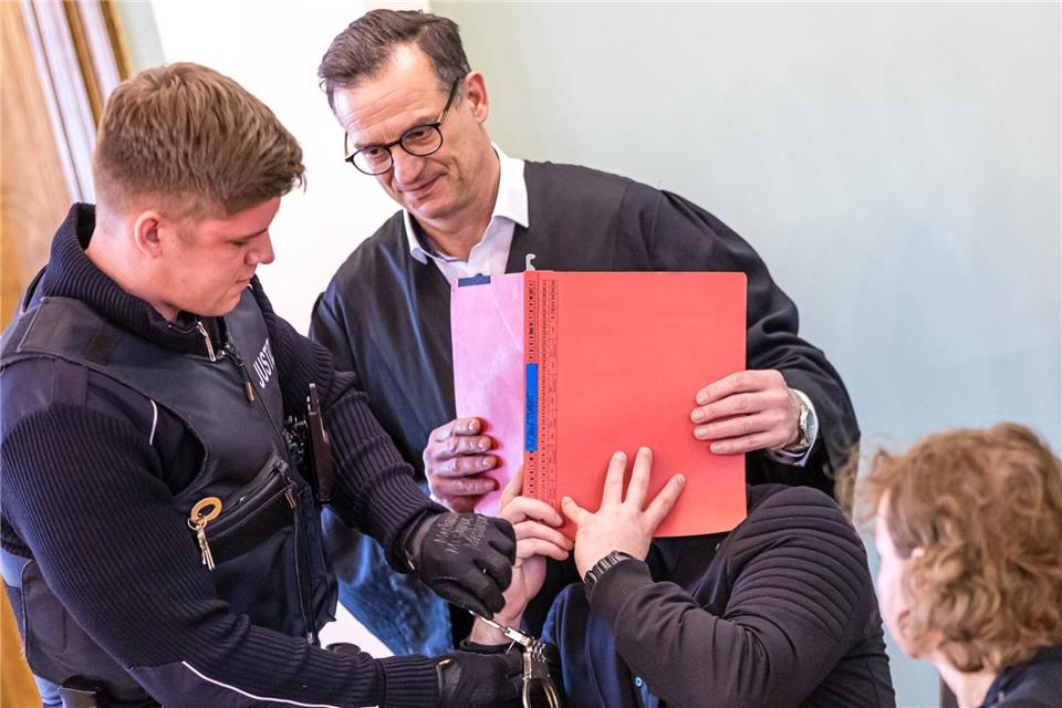 Auch am zweiten Verhandlungstag im Prozess um einen tödlichen Polizei-Einsatz gegen Autodiebe verdeckt der Angeklagte sein Gesicht. Frank Hammerschmidt/dpa