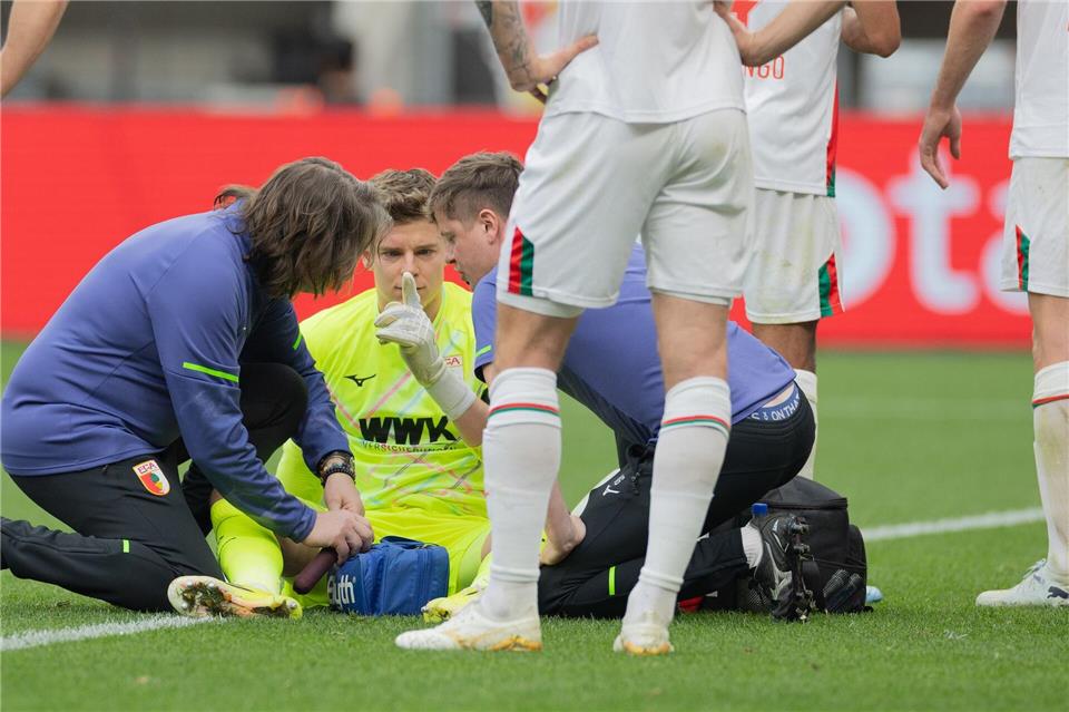 Auch eine kurze Behandlungspause nach einer Abwehr mit dem Kopf konnte Augsburgs Keeper Finn Dahmen nicht aus dem Rhythmus bringen. Rolf Vennenbernd/dpa