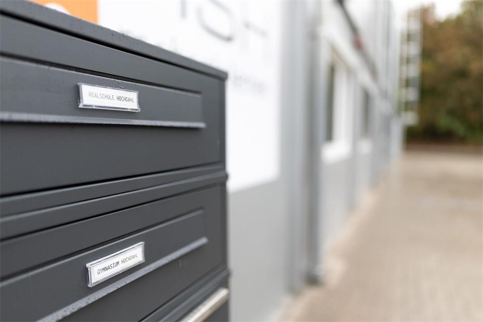 Auf dem Briefkasten im Schuldorf stehen die Namen der beiden Schulen. Fabian Strauch/dpa