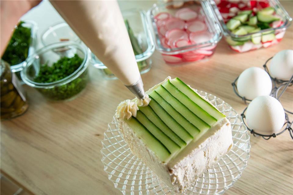 Auf der Gurkenschicht wird mit einem Spritzbeutel Frischkäse in Rosettenform aufgespritzt. Christin Klose/dpa-tmn