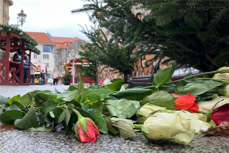 Auf der Zufahrt zum Weihnachtsmarkt liegen Blumen neben Gedenkplatten, die an die sechs Opfer erinnern. Simon Kremer/dpa