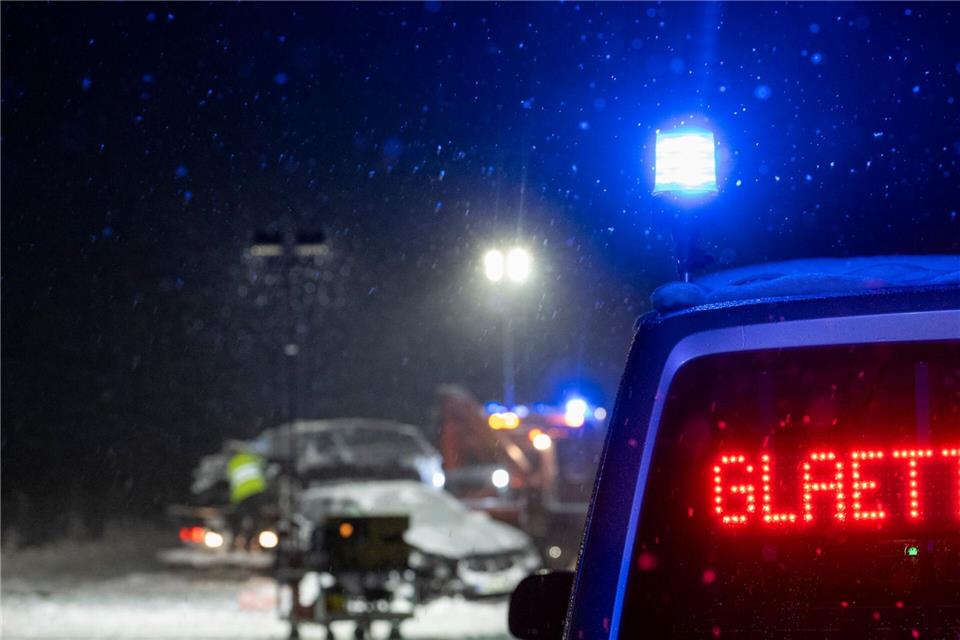 Auf der verschneiten Bundesstraße 12 warnt an einer Unfallstelle ein Polizeifahrzeug vor Glätte. Stefan Puchner/dpa