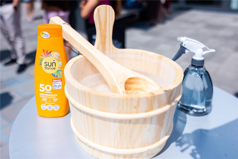 Auf einem Tisch stehen bei der Protestaktion „Saunieren statt Studieren“ eine Flasche Sonnencreme mit Lichtschutzfaktor 50 sowie ein typisches Aufguss-Gefäß mit Löffel.Laszlo Pinter/dpa