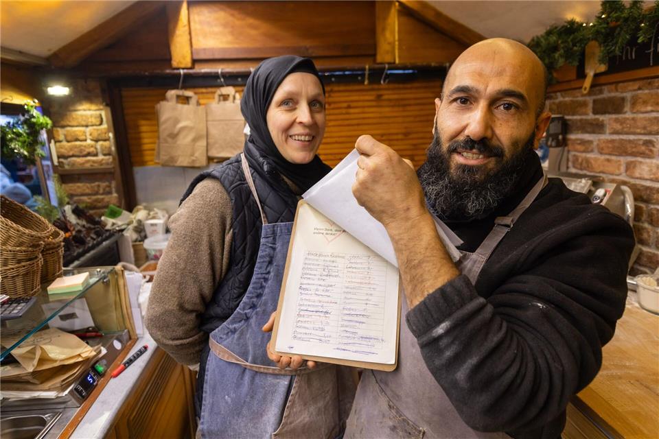 Auf einer Liste notieren Bayram Dalkilic und seine Frau Isabell Geldspenden, mit denen Kunden kostenloses Essen für bedürftige Menschen finanzieren. (Archivfoto) Christian Lademann/dpa