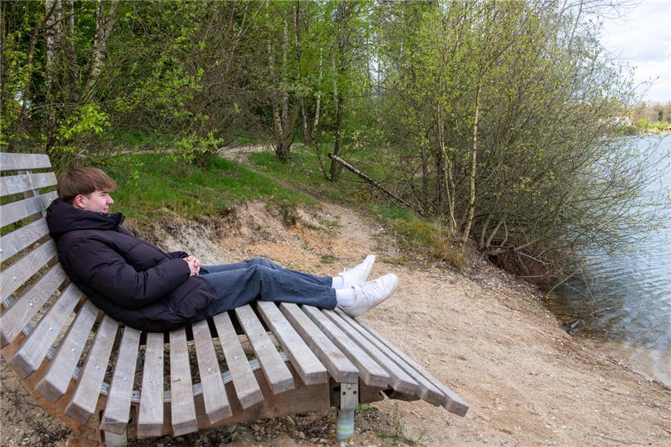 Auf einer modernen großen Bank sitzt Felix Bußkamp.