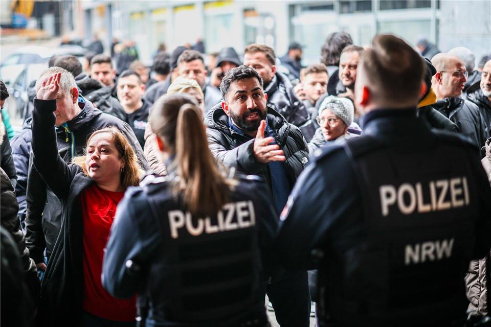 Aufgebrachte Kunden diskutieren vor der Sparkassenfiliale in Buer mit Polizeibeamten nach der Räumung des Vorraums der Filiale.Christoph Reichwein/dpa