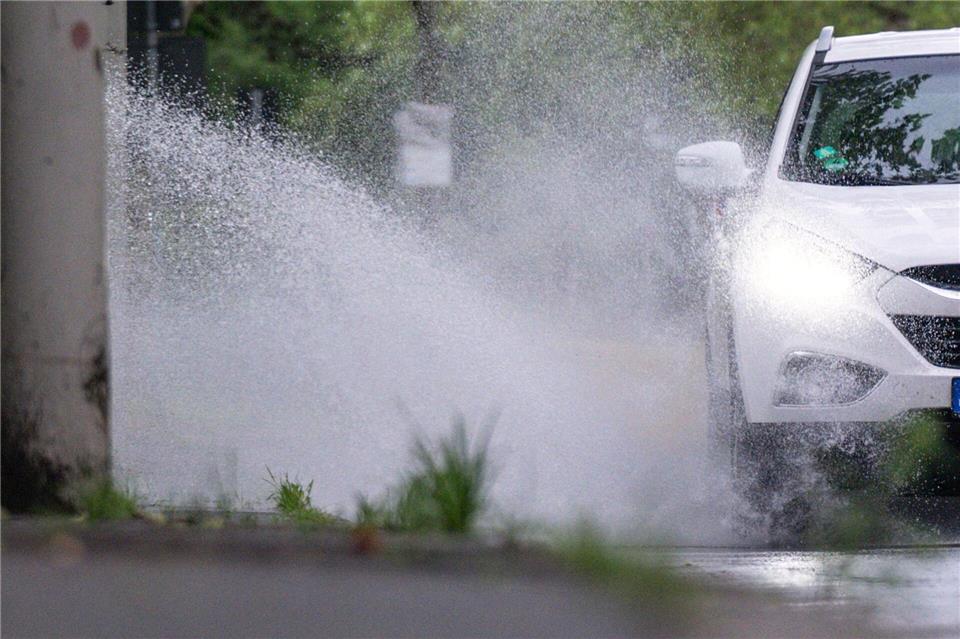 Aufgepasst an der Bordsteinkante: Ein Auto fährt bei Regenwetter eine Straße entlang. Benjamin Westhoff/dpa