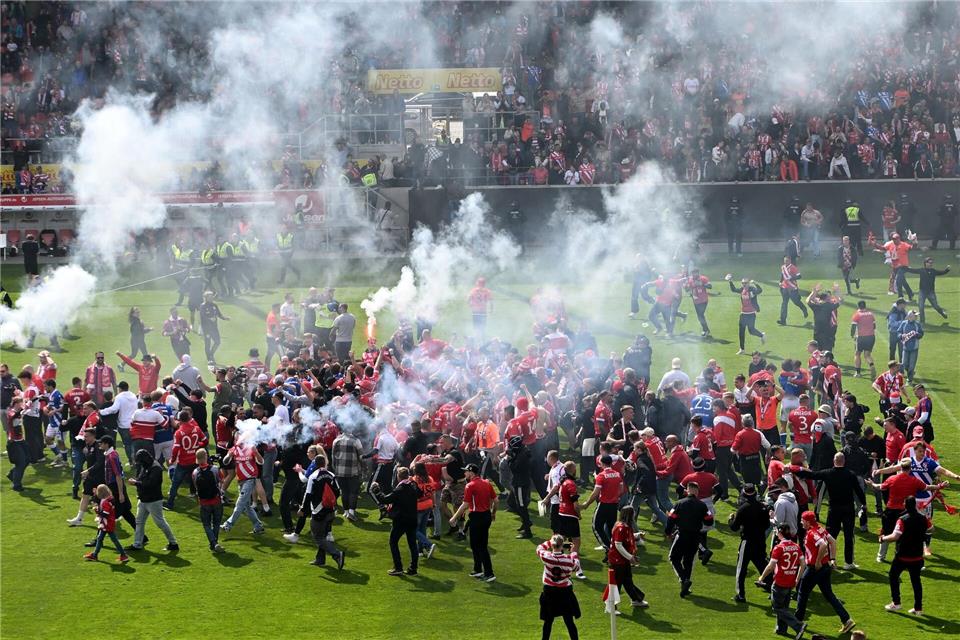 Aufstiegsfeier mit Pyrotechnik: Fans des FC Energie Cottbus auf dem Spielfeld in Regensburg.Jens Niering/dpa