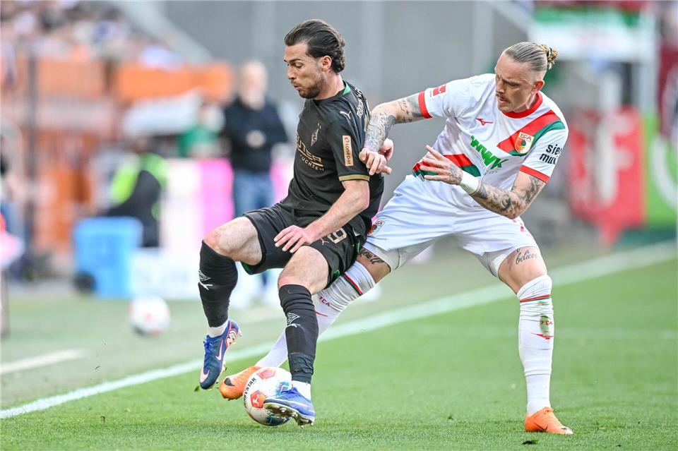 Augsburg Marius Wolf (r) nimmt dem Gladbacher Joe Scally den Ball ab.Harry Langer/dpa