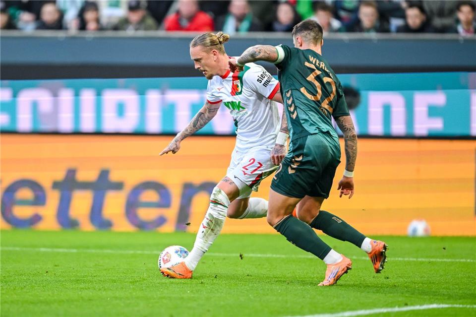 Augsburgs Marius Wolf (l) im Zweikampf mit Werder-Verteidiger Marco Friedl. Harry Langer/dpa