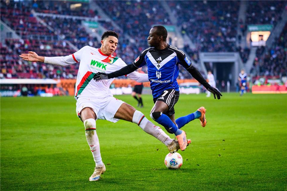 Augsburgs Noahkai Banks im Zweikampf mit Jean-Luc Dompé vom HSV.Tom Weller/dpa