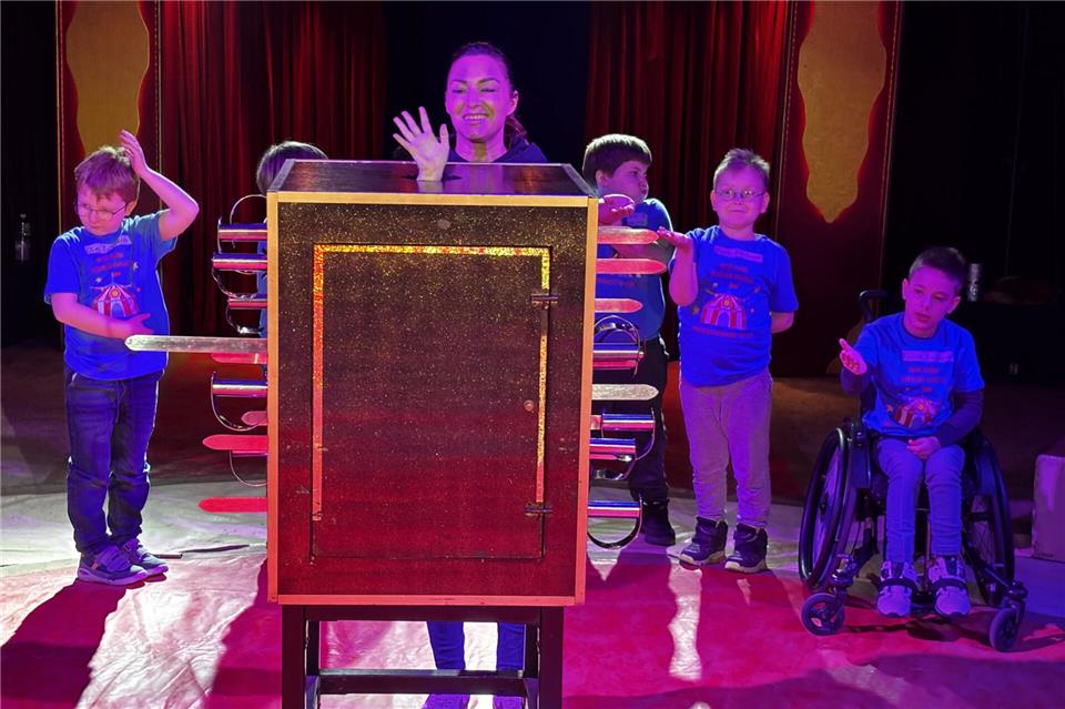 Aus der mit Schwertern gespickten Kiste winkt Holly dem Publikum zu.