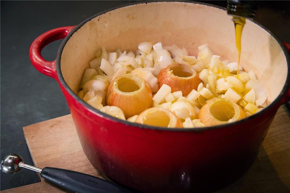 Ausgehöhlte und geschnittene Zwiebeln kommen zusammen mit Olivenöl zum langsamen Garen, dem sogenannten Confieren, für 1,5 Stunden in den Topf.Christin Klose/dpa-tmn