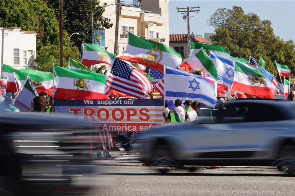 Autos fahren in Los Angeles an Demonstranten vorbei.Ethan Swope/AP/dpa