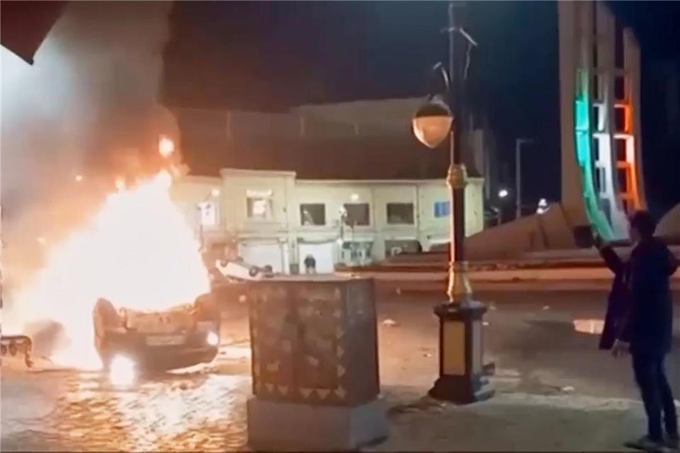 Autos und auch Gebäude sollen bei den Protesten im Iran in Flammen aufgegangen sein.Uncredited/Iran state TV/AP/dpa