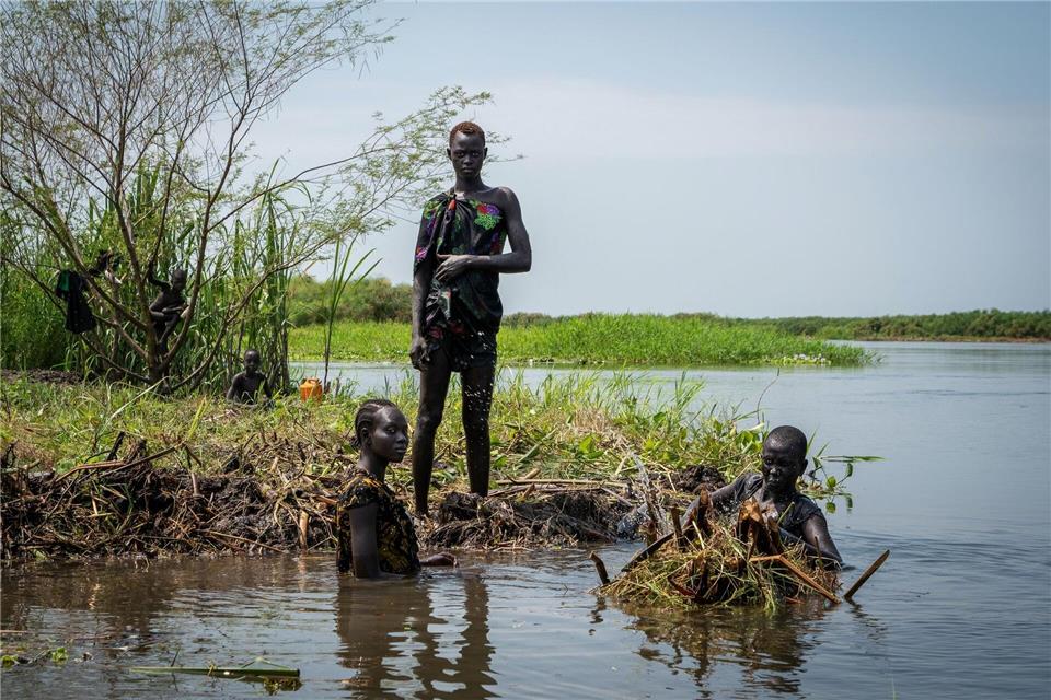 Ayen Deng Duot (r) und ihre Familie befestigen ihre Insel mit Pflanzen und Schlamm aus dem Sumpf, um zu verhindern, dass ihr Haus am Nil überflutet wird.Florence Miettaux/AP/dpa