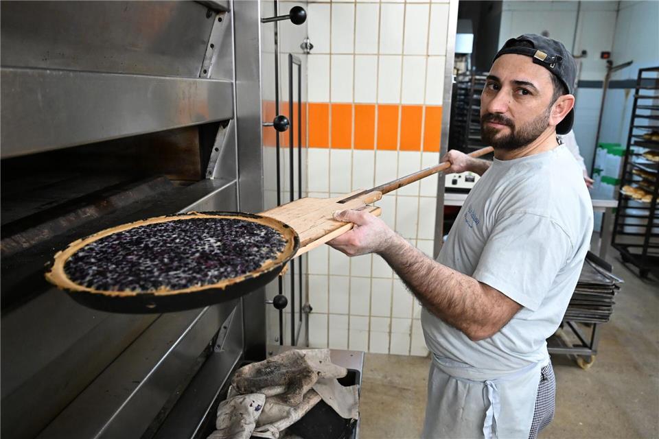 Bäcker Sulaiman Shapal nimmt ein Blech mit Blaubeerkuchen aus einem Ofen in einer Backstube. Er ist aus Syrien nach Deutschland geflohen.Michael Brandt/dpa