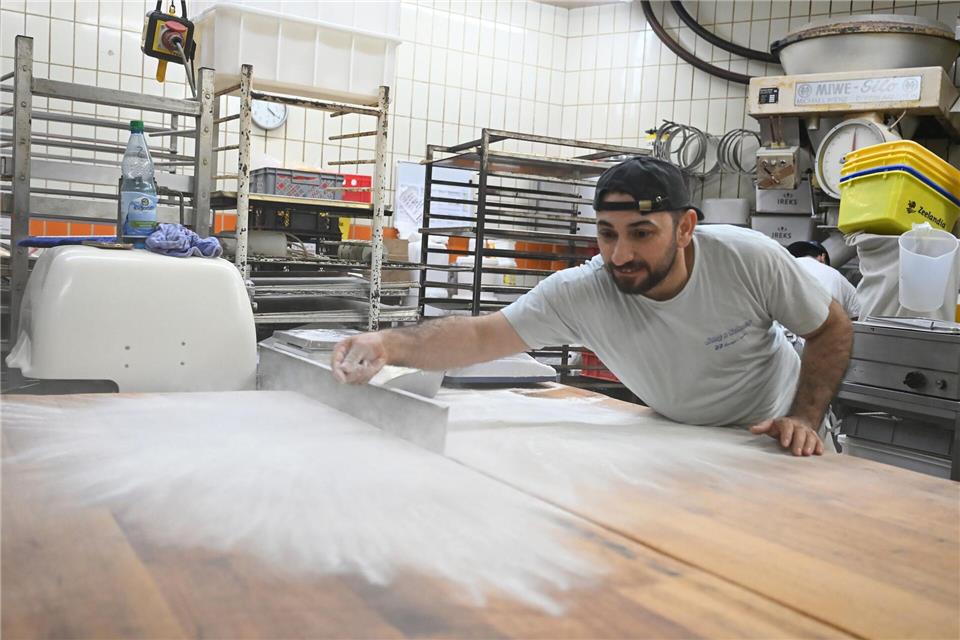 Bäcker Sulaiman Shapal streut Mehl auf einen Tisch in einer Backstube.Michael Brandt/dpa