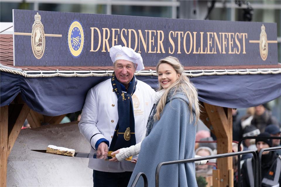 Bäckermeister Reiner Israel und Stollenmädchen Johanna Worm präsentieren zum Dresdner Stollenfest ein Stück vom Riesenstollen.Sebastian Kahnert/dpa