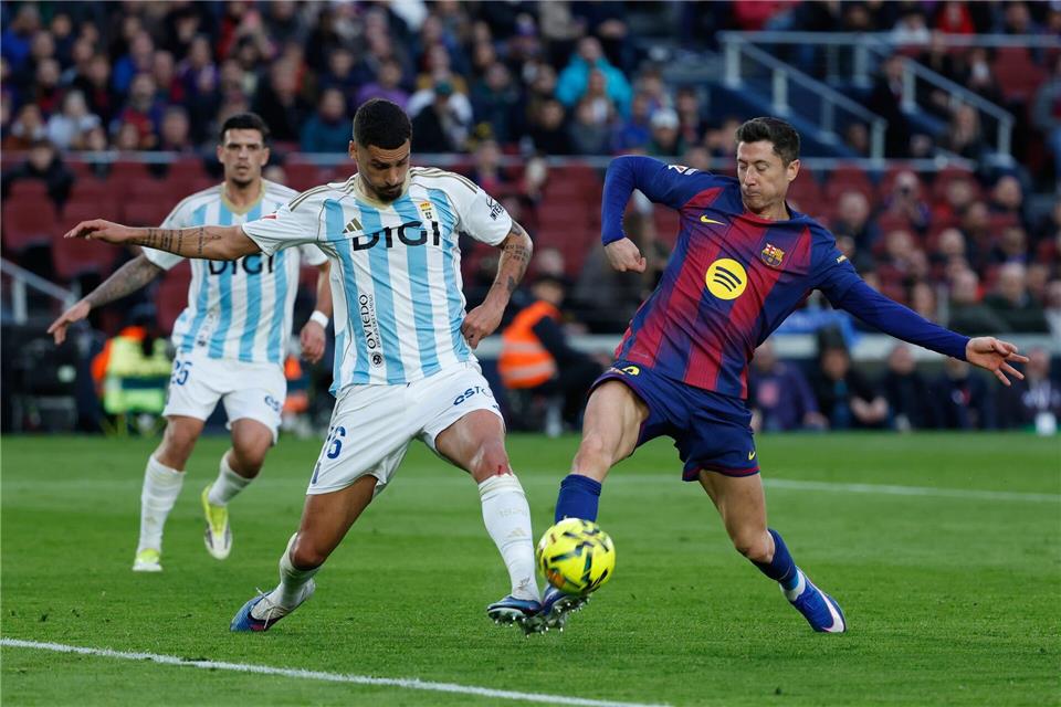 Barcelonas Robert Lewandowski (r) im Zweikampf mit David Carmo von Real Oviedo.Joan Monfort/AP/dpa