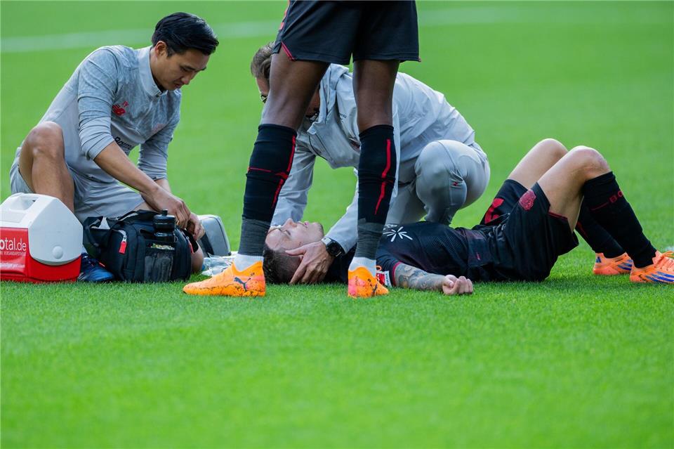 Bayer Leverkusens Kapitän Alejandro Grimaldo liegt nach einem Zusammenprall auf dem Boden. Rolf Vennenbernd/dpa