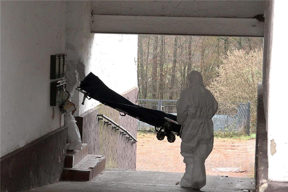 Beamte der Spurensicherung bringen eine Trage in ein Wohnhaus. Thorsten Kremers/dpa