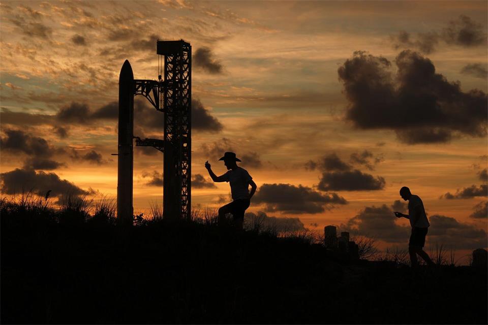 Bei Sonnenuntergang versammeln sich Menschen vor der Mega-Rakete „Starship“.Eric Gay/AP/dpa