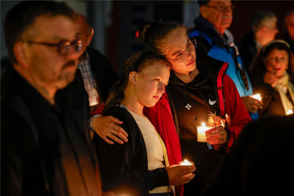 Bei der Trauerfeier an der Gedenktafel an der Evangelischen Stadtkirche, gedenken Menschen der Opfer des Terroranschlags und halten brennende Kerzen in den Händen.Thomas Banneyer/dpa