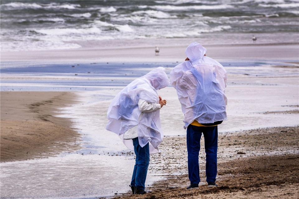 Bei teils stürmischem Wetter ließen sich Menschen am Strand durchpusten.Jens Büttner/dpa