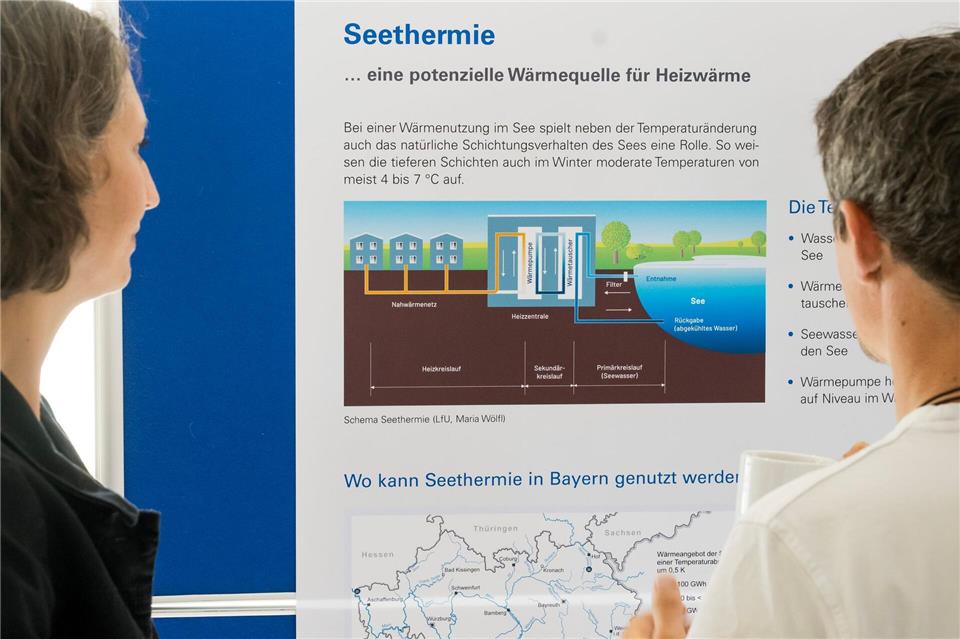 Besucher der Abschlussveranstaltung betrachten das Schema einer Seethermie-Anlage. Tobias Hase/dpa