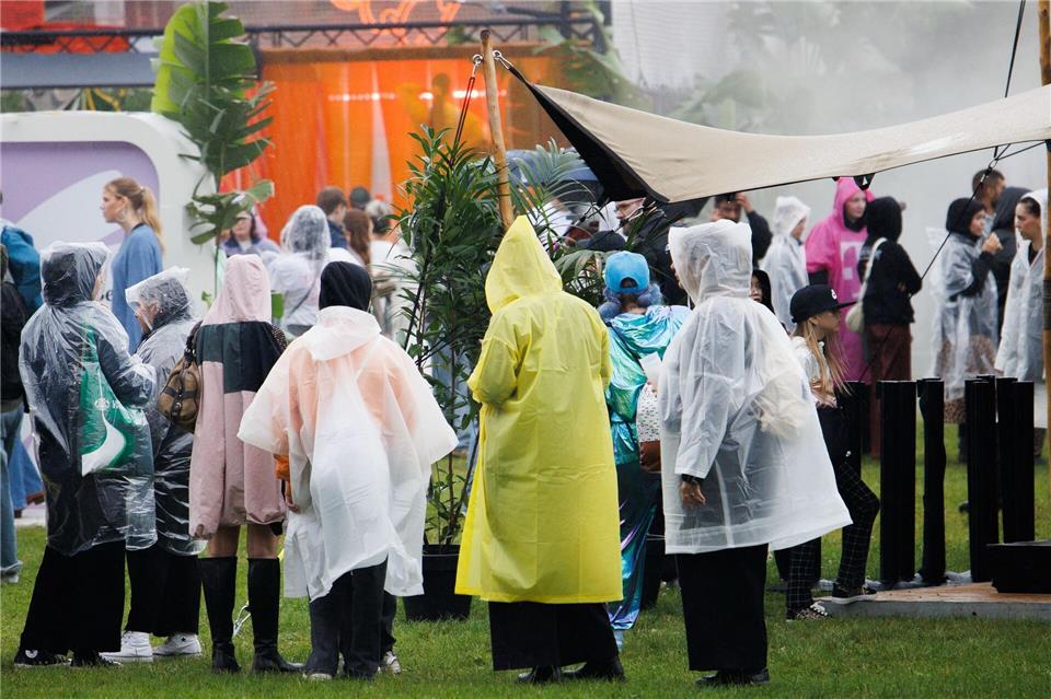 Besucher gehen im Regen zu Ständen beim zweitägigen Musikfestival Lollapalooza auf dem Gelände des Olympiaparks.Carsten Koall/dpa